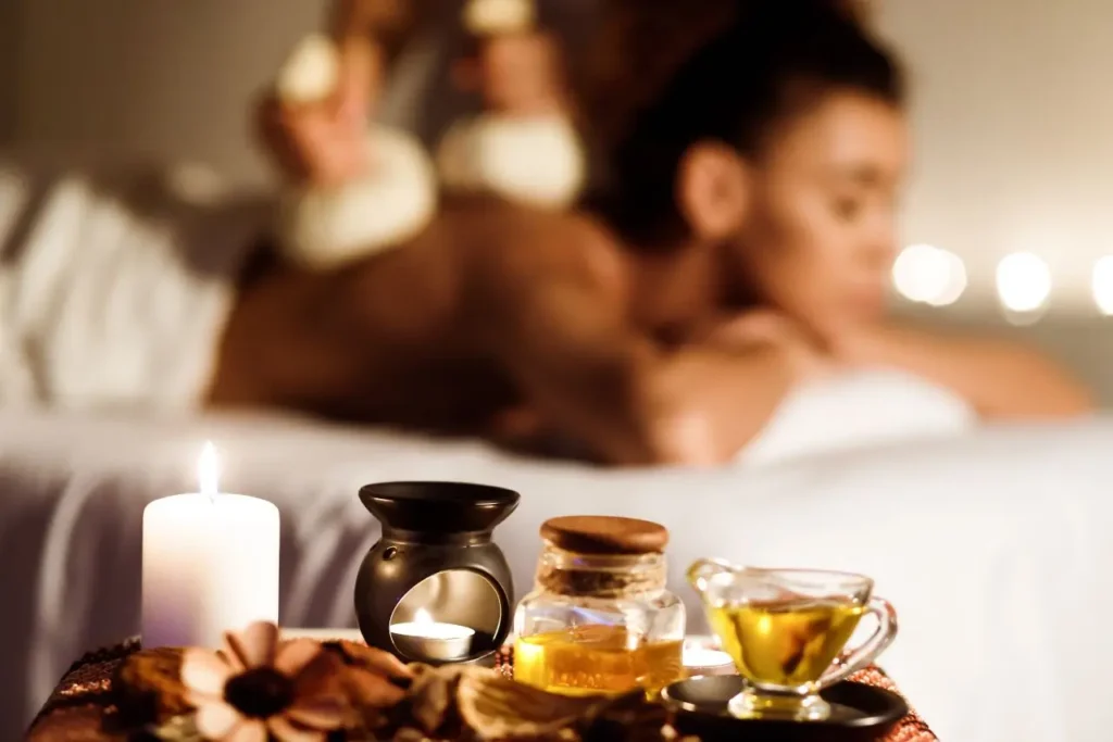 Woman receiving aromatherapy massage with oils and candles in the background, offering total body relaxation in Basavanagudi